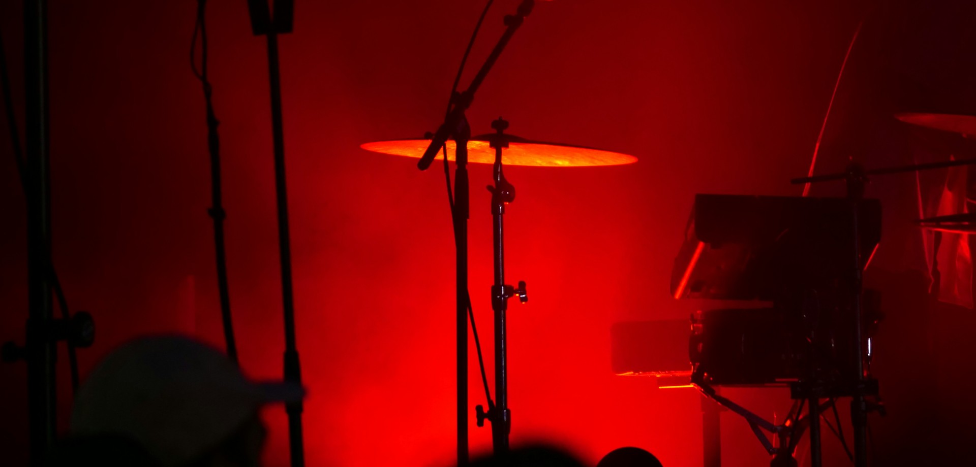 Ausschnitt einer Bühne mit Mikrofonstände und Becken