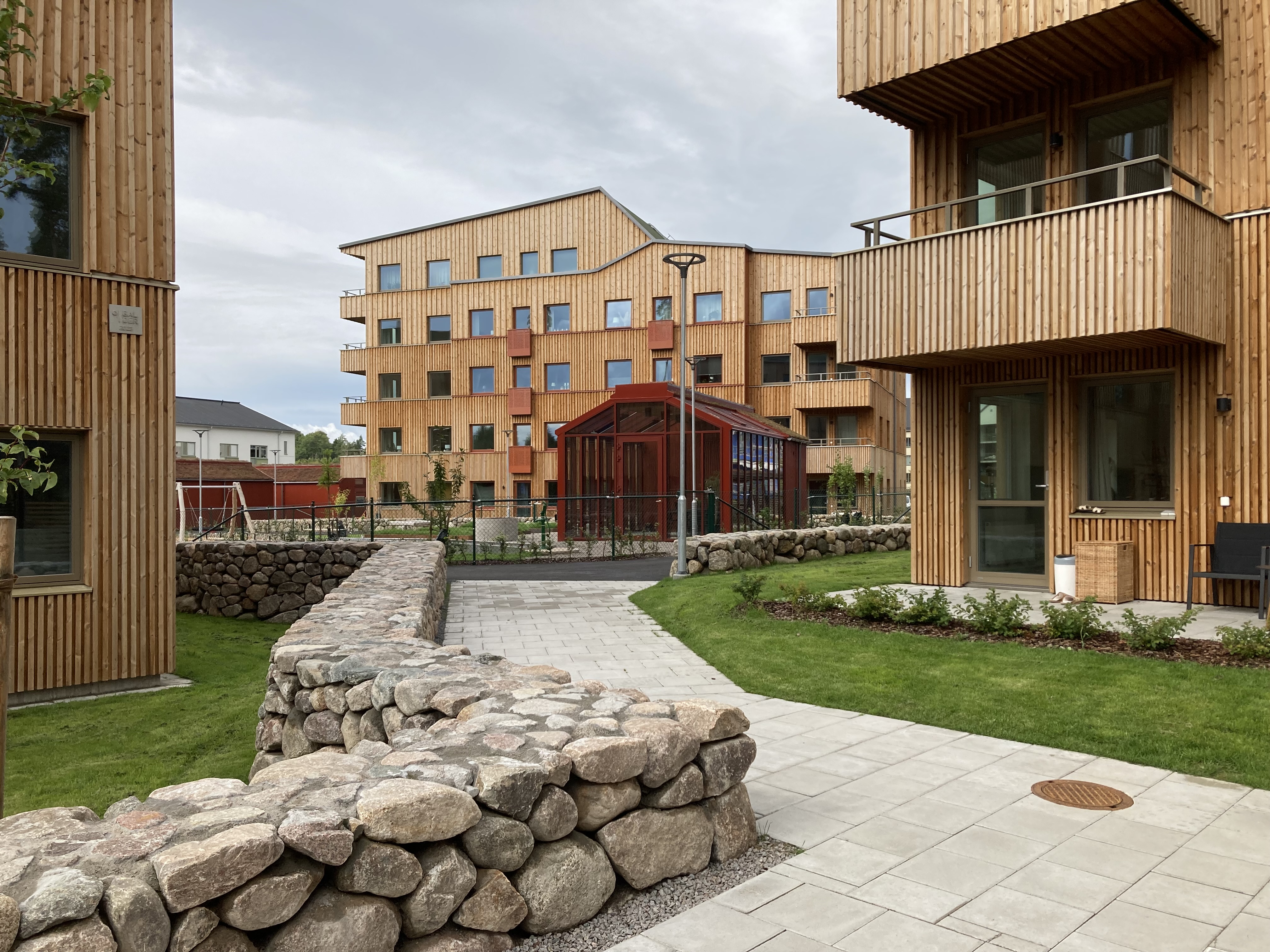 Ein gepflasterter Weg führt zwischen mehreren Holzhäusern hindurch.