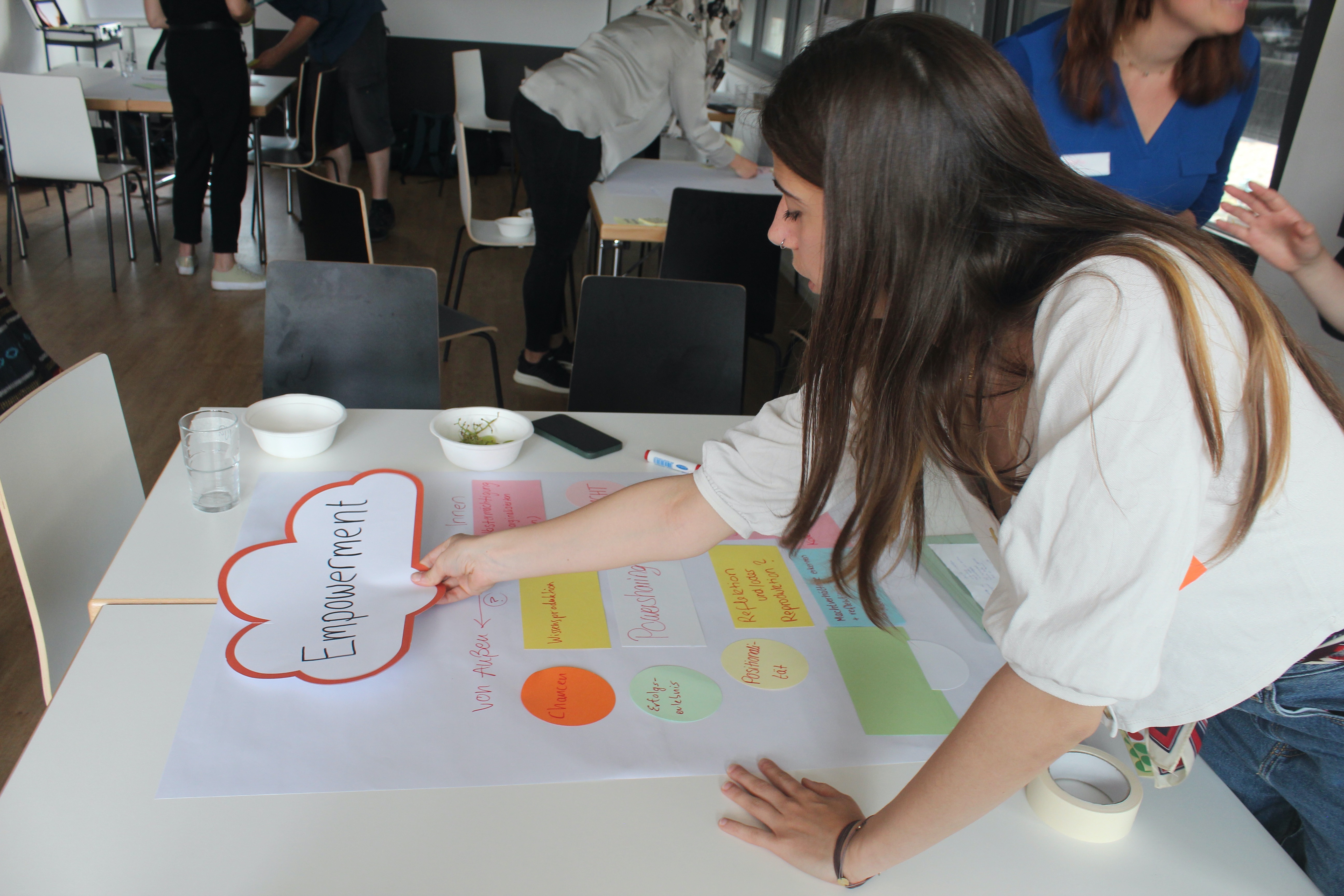 Eine Frau schreibt etwas auf eine als Wolke ausgeschnittene Karte