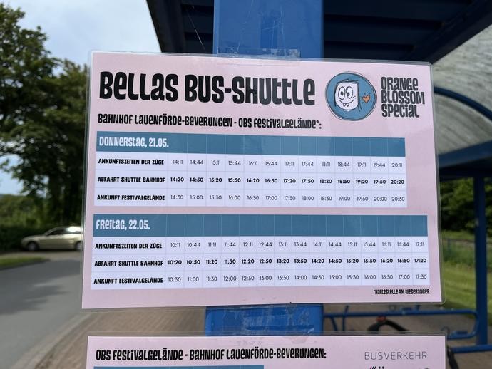 Aushang mit Fahrplan für „Bellas Bus-Shuttle“ an einer Haltestelle.