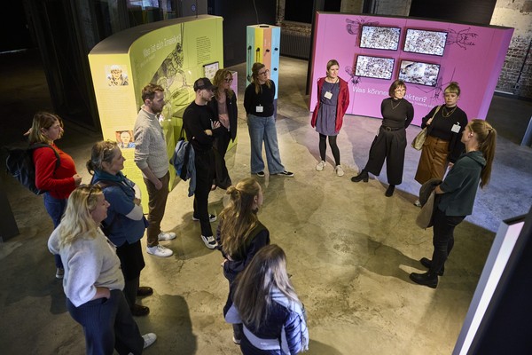 Teilnehmende stehen während einer Führung durch ein Museum im Kreis.