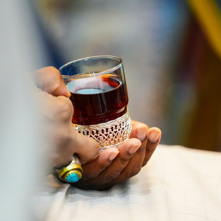 Ein Glas mit Tee wird in zwei Händen gehalten