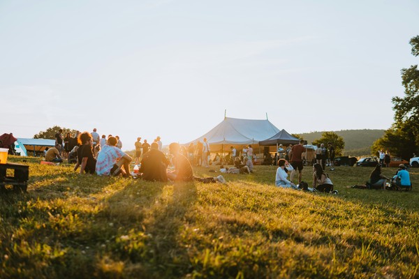 Wiese, auf der Menschen im Sonnenuntergang sitzen