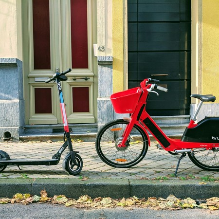 Auf dem Gehweg stehen links ein E-Scooter und rechts ein Leihfahrrad