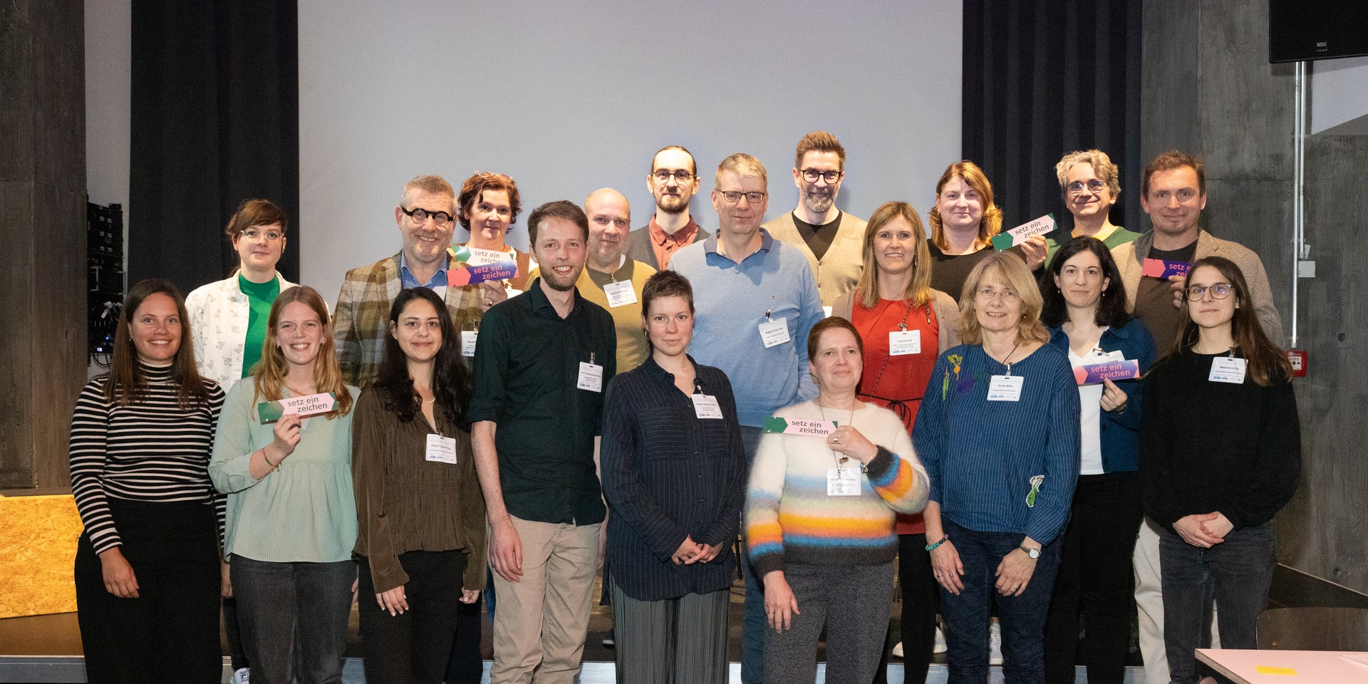 Gruppenfoto von Personen vor einer großen Präsentationsleinwand.
