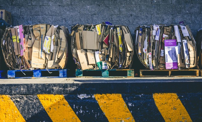 Drei geschnürte Pakete mit Altpapier stehen auf einer Anlieferungsrampe.