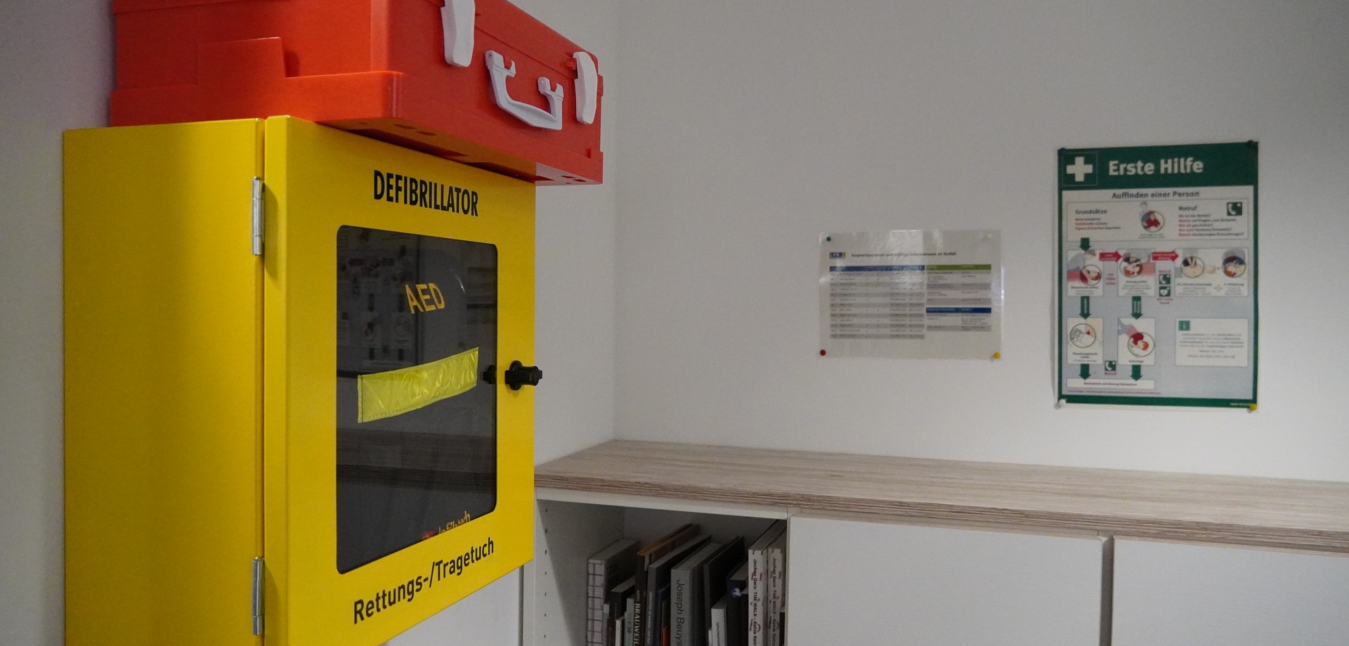 Ein Defibrillator und ein Notfallplan in einem Büro.