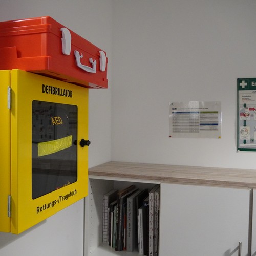 Ein Defibrillator und ein Notfallplan in einem Büro.