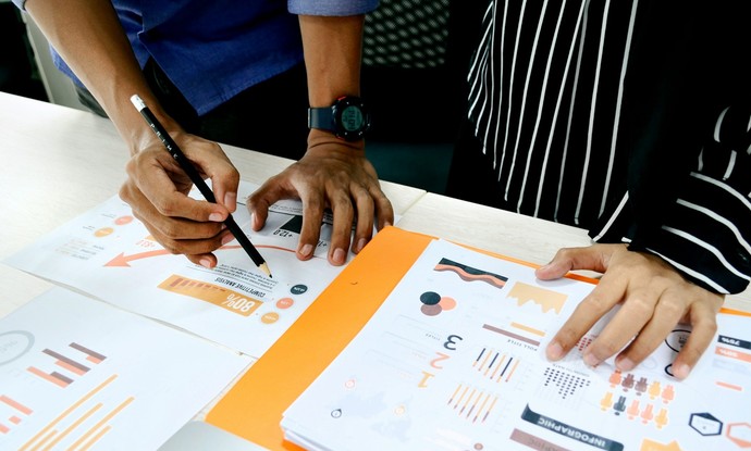 Hände zeigen auf Dokumente mit verschiedenen Statistiken