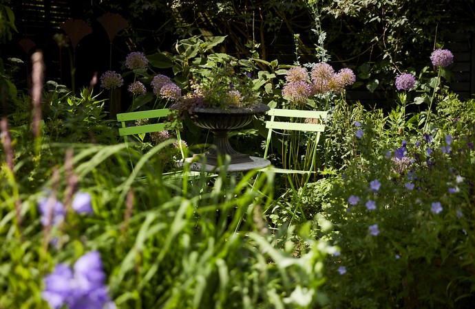 Garten mit zwei gelben Gartenstühlen und Blumen im Hintergrund