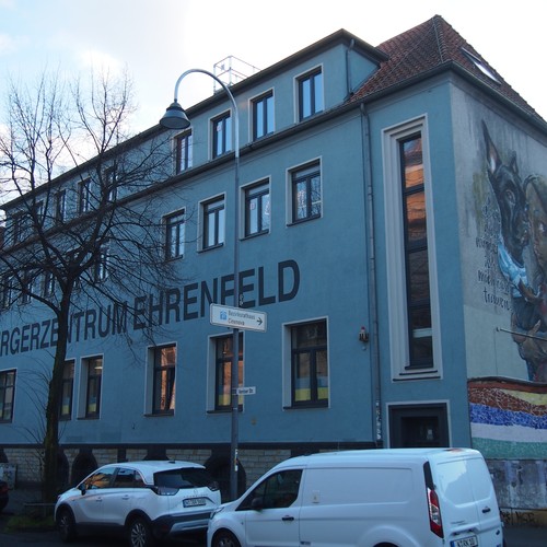 Ein Gebäude auf dem in großen Buchstaben Bürgerzentrum Ehrenfeld steht. Auf der Seitenwand ist ein großes Graffiti von einem Mädchen und ihrem Hund zu sehen.