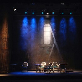 Theaterbühne mit Personen drauf und mit blauem Licht ausgeleuchtet