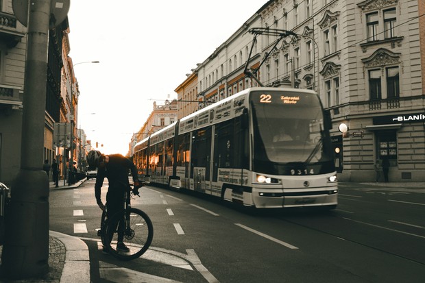 Links steht ein Fahrradfahrer auf einer Straße, rechts fährt eine Straßenbahn