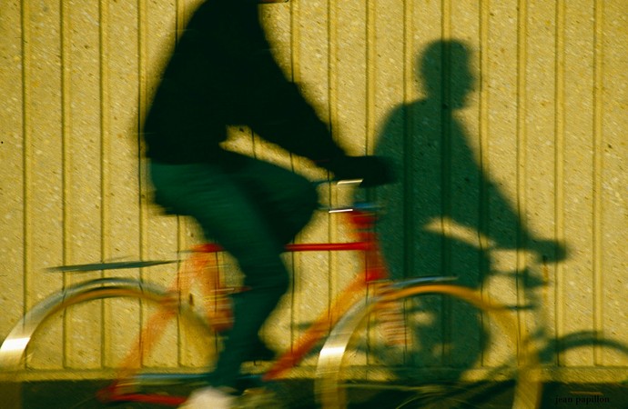 Fahrender Fahrradfahrer wirft Schatten auf gelbe Wand